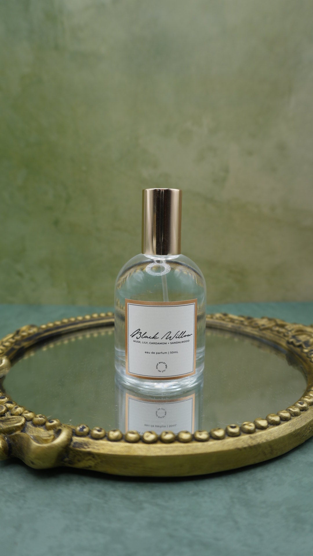 Bailey Bee Black Willow Eau de Parfum 50ml bottle with gold cap on an antique gold mirrored tray, notes of musk, lily, cardamom and sandalwood