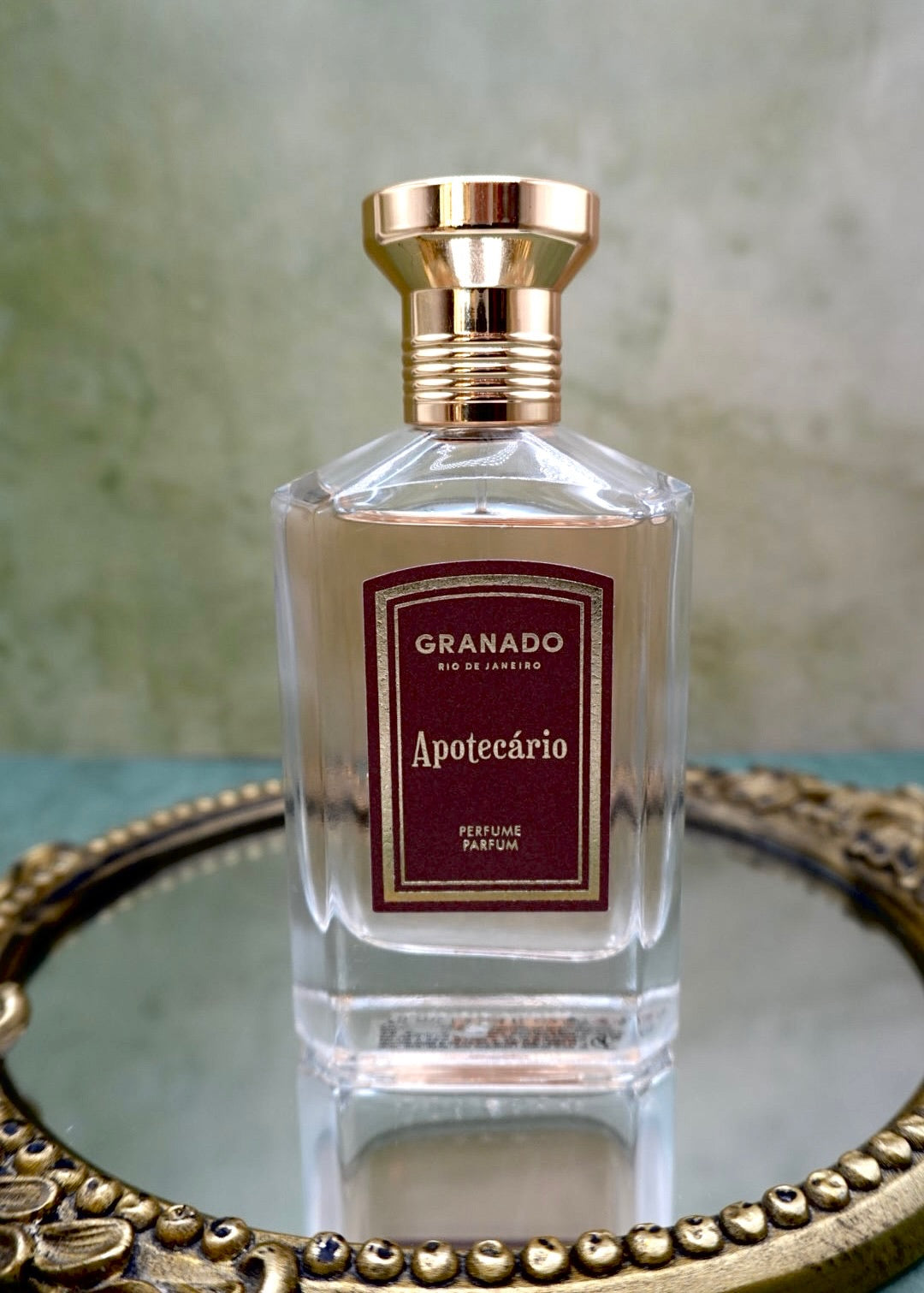 Granado Apotecário perfume upright bottle with gold cap on patterned marquetry tiles, notes of bergamot, cardamom, leather, black tea, myrrh and tonka